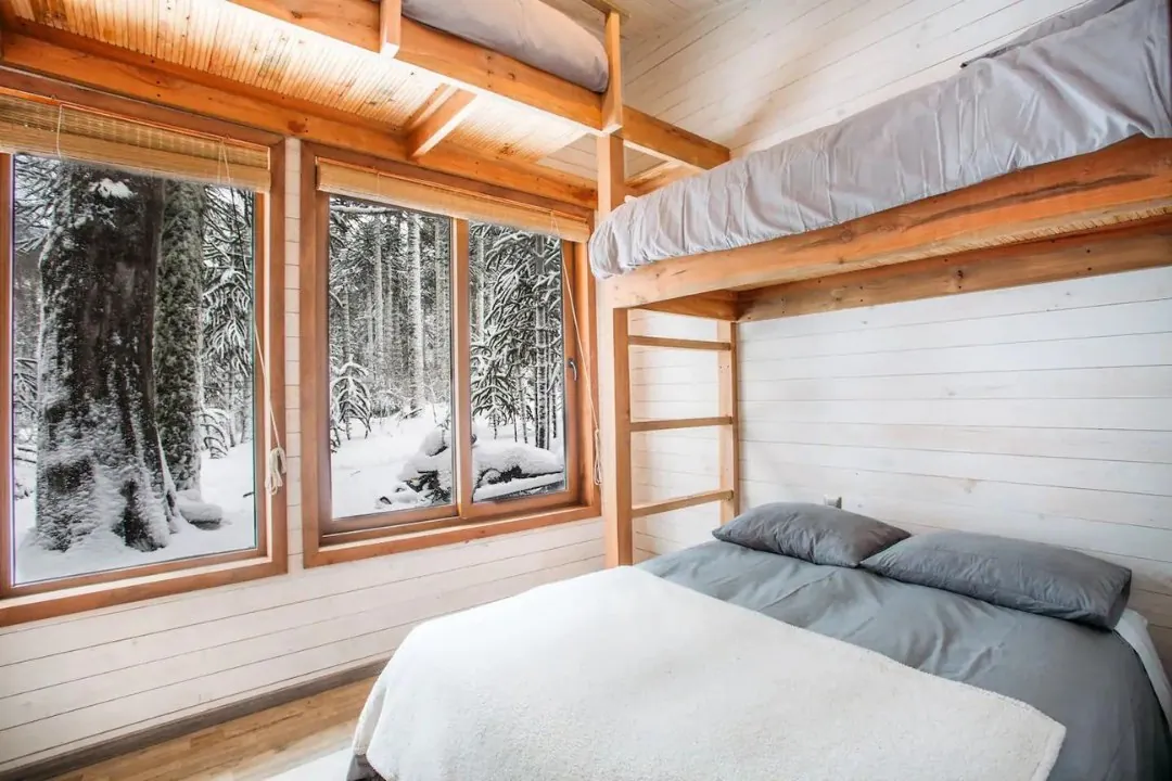 Interior de Casa Legarreta: revestimiento de madera y ventanas al bosque