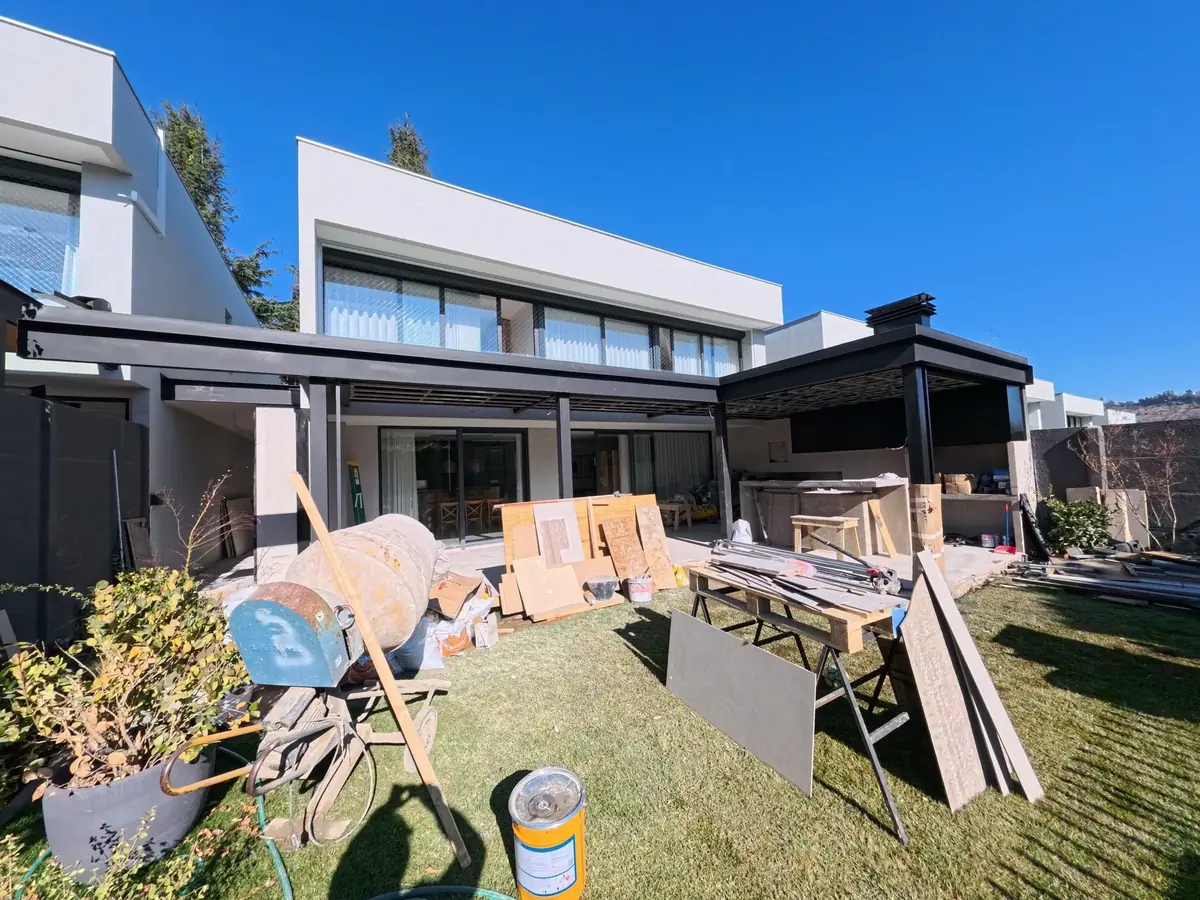 Quincho RJ en Las Condes construido: pérgola metálica, cielo de madera y asador, abierto al jardín