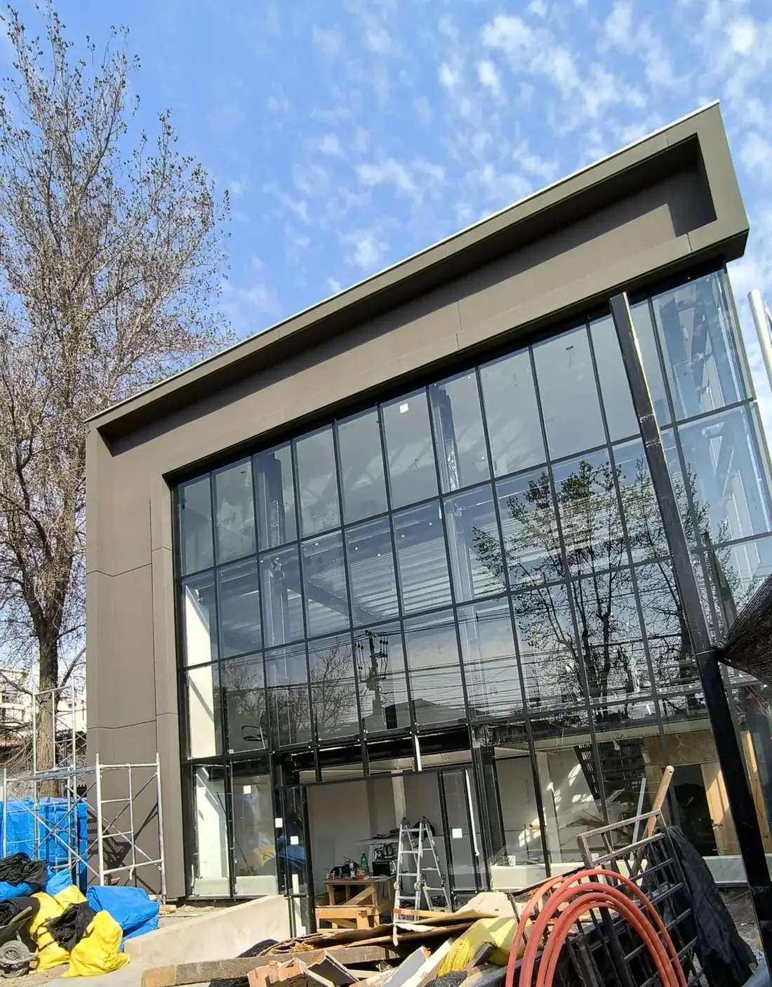 Fachada vidriada de doble altura terminada, con estructura metálica negra, en Ñuñoa