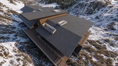 Casa El Arrayán: vivienda de cubiertas quebradas y terrazas de madera, implantada en la ladera