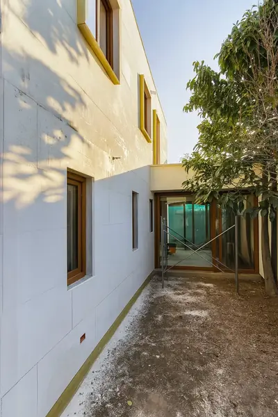 Casa MJadue en Las Condes: fachada en ejecución con revestimiento y ventanas de madera