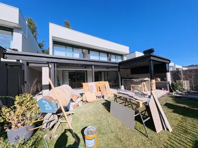 Quincho RJ en Las Condes construido: pérgola metálica, cielo de madera y asador, abierto al jardín